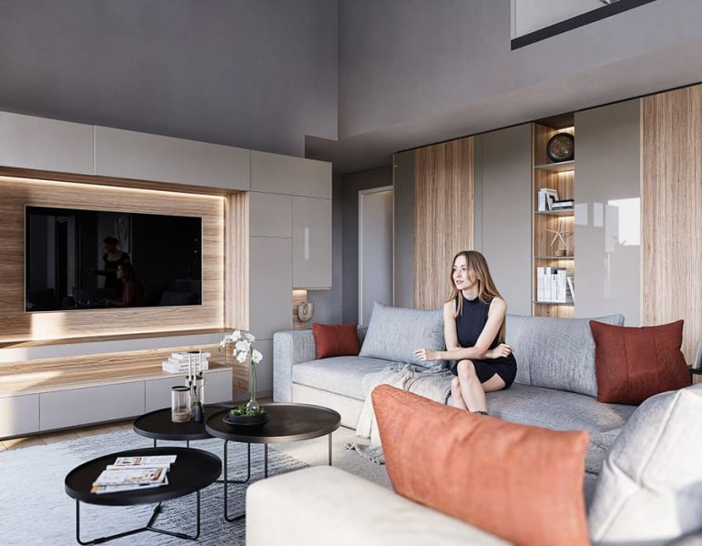 Soggiorno moderno: donna seduta su divano grigio, pareti chiare, mobili in legno, TV incorniciata e cuscini color terracotta