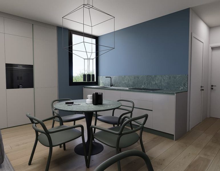 Cucina moderna con tavolo rotondo e sedie verdi, piano in marmo, elementi bianchi e una parete blu, illuminazione geometrica al soffitto.