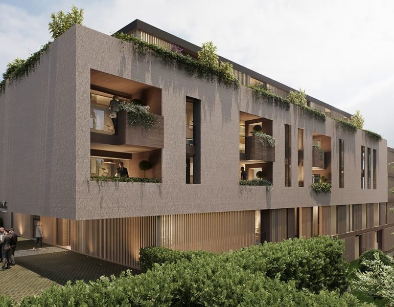Edificio moderno a due piani con cortili interni e balconi, piante sui davanzali e una facciata in cemento, contesto urbano verde.
